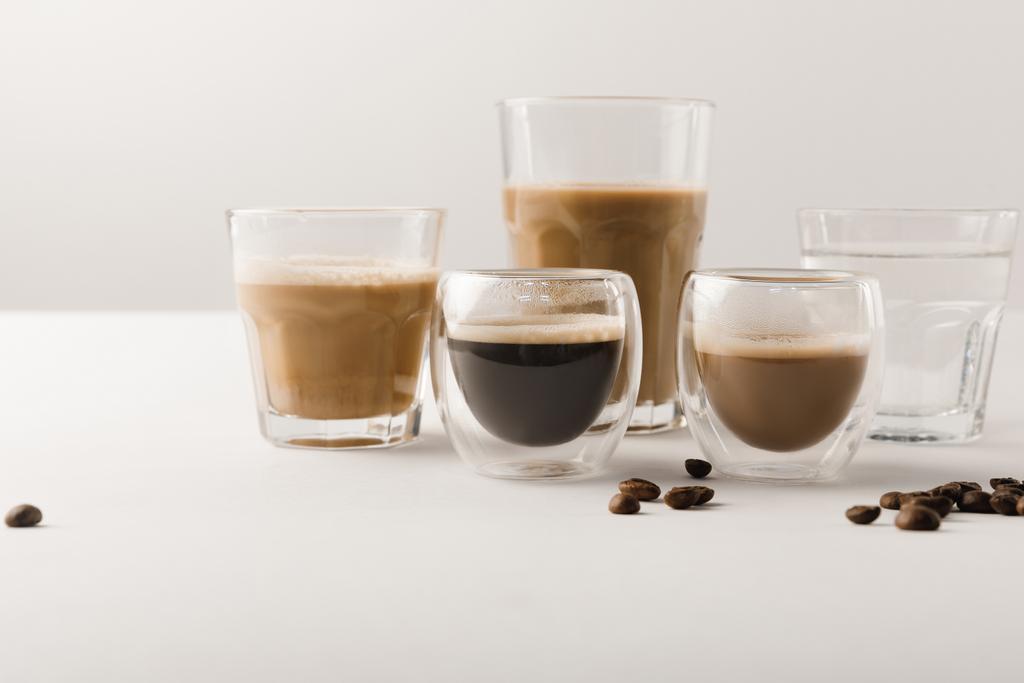 Joukko kuppeja valikoituja kahvijuomia valkoisella taustalla
 - Valokuva, kuva