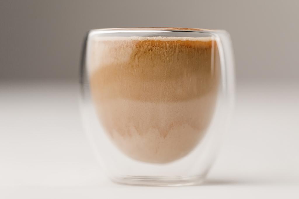 Szkło Kubek wypełniony kawy z mlekiem na białym tle - Zdjęcie, obraz