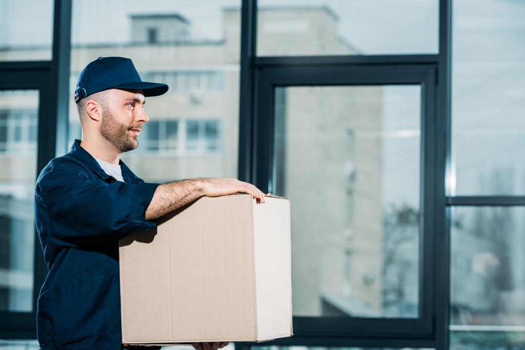 Giovane uomo di consegna che trasporta scatola di cartone
 - Foto, immagini