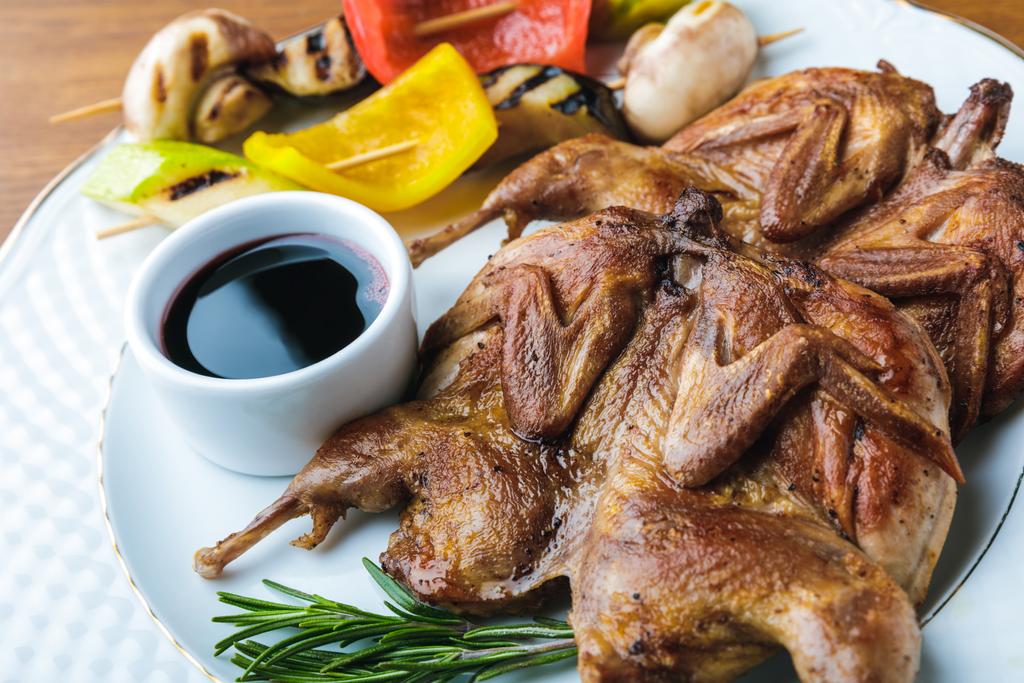 крупным планом вид жареных цыплят с овощами на гриле и соусом на тарелке
 - Фото, изображение