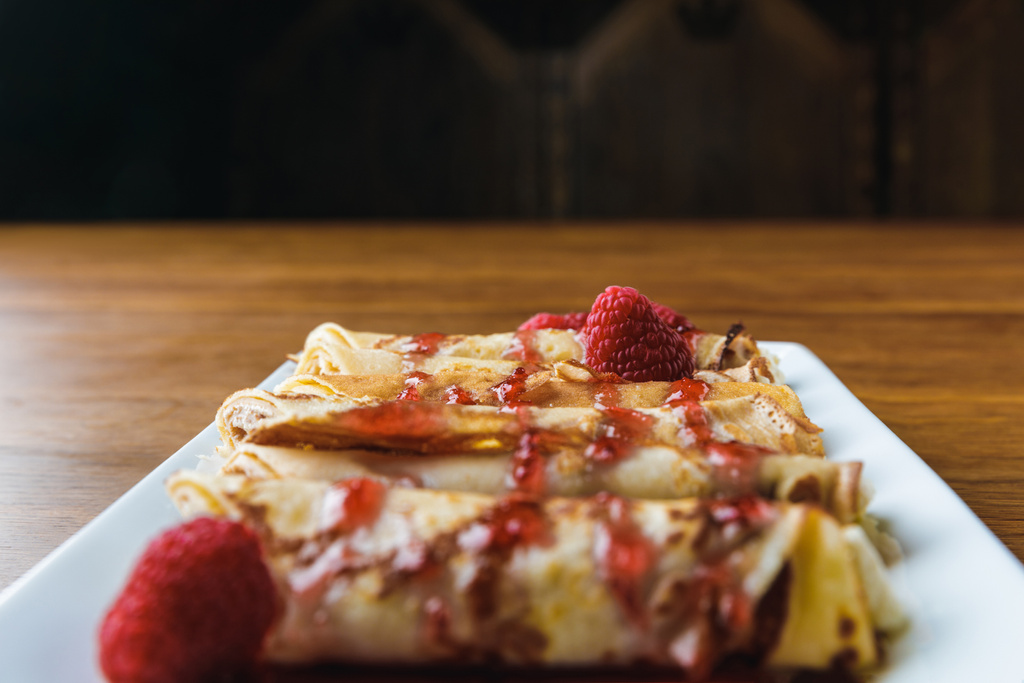 close-up view of sweet rolled pancakes with raspberries and jam - Photo, Image