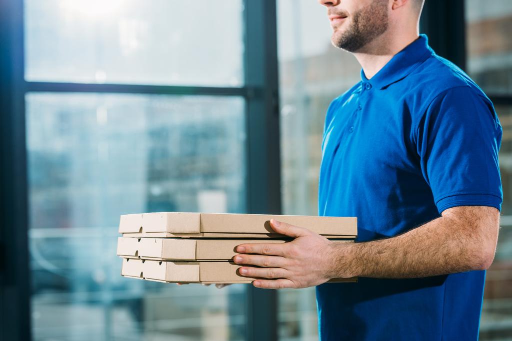 Крупный план доставки парень держит пиццу в коробках
  - Фото, изображение