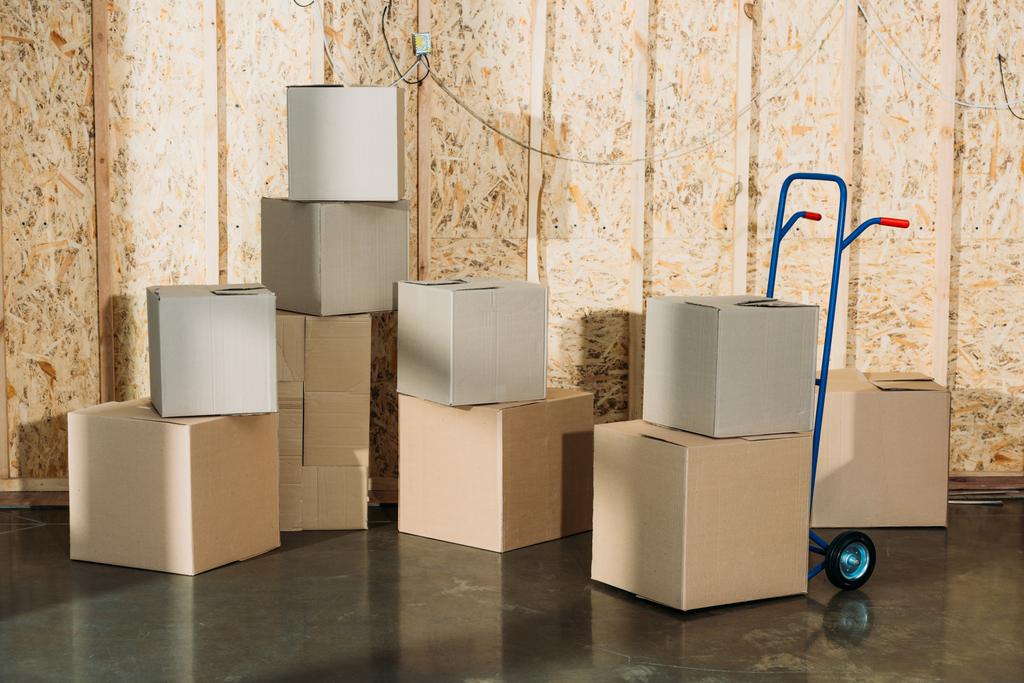 Cardboard boxes and hand truck in warehouse room - Photo, Image