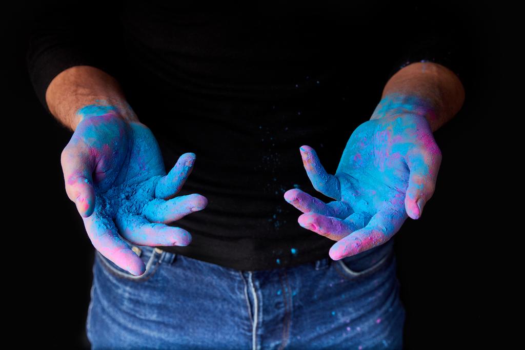 обрезанный вид человека с синей традиционной краской цвета голи на руках, изолированный на черном
 - Фото, изображение