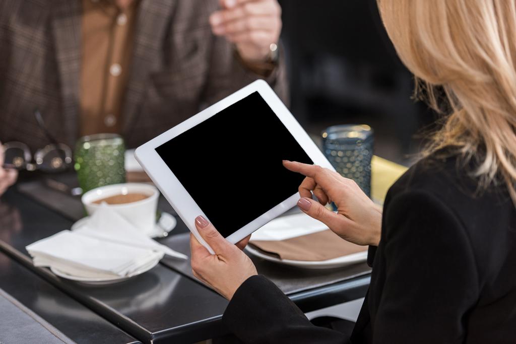 Oříznout záběr podnikatelka pomocí tabletu během obchodní schůzky s kolegy v kavárně - Fotografie, Obrázek