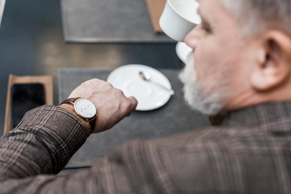 valikoiva painopiste vanhempi liikemies tarkkailun aikaa istuessaan pöydässä kahvilassa
 - Valokuva, kuva