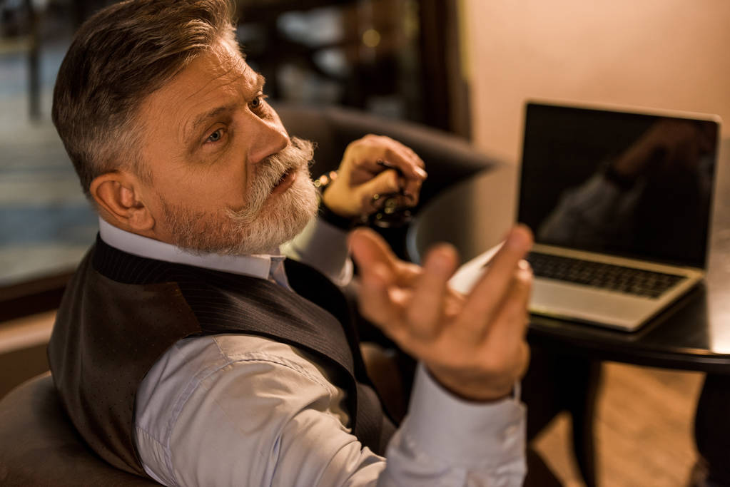 Старший бородатый бизнесмен зовет официанта в кафе
 - Фото, изображение