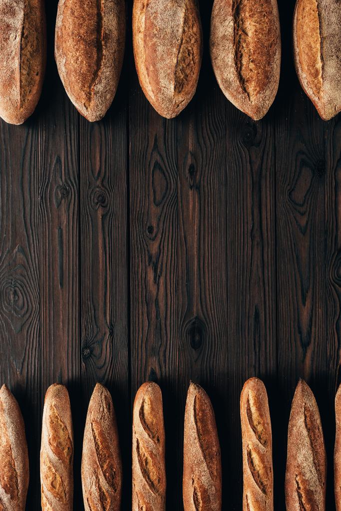 top view of arranged loafs of bread and french baguettes on wooden surface - Photo, Image