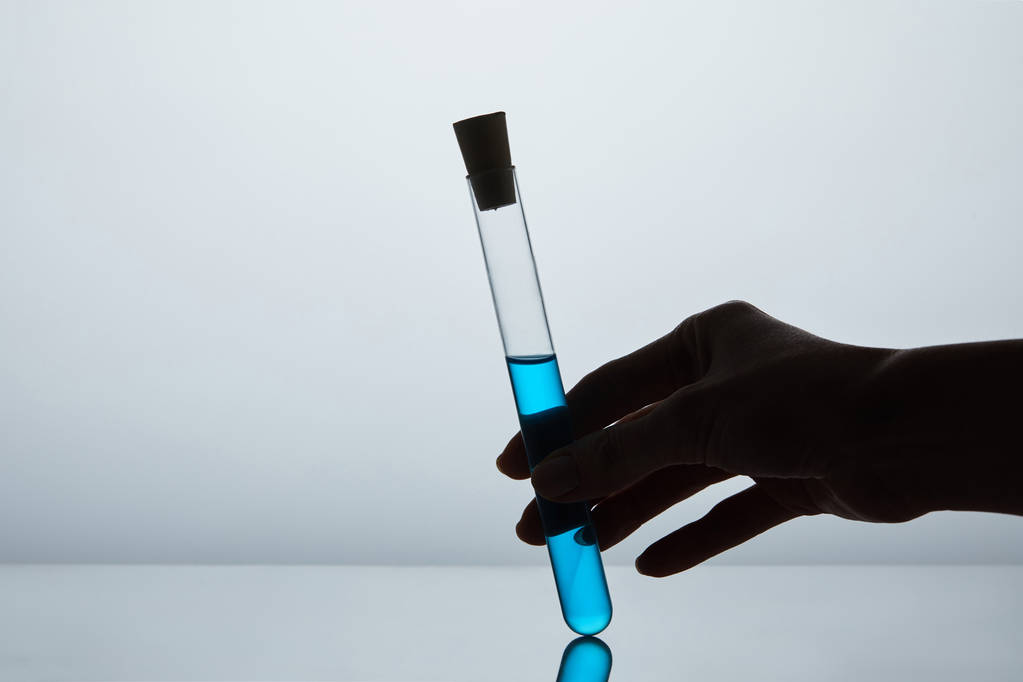 plan recadré d'une femme tenant un tube à essai rempli de liquide bleu
 - Photo, image