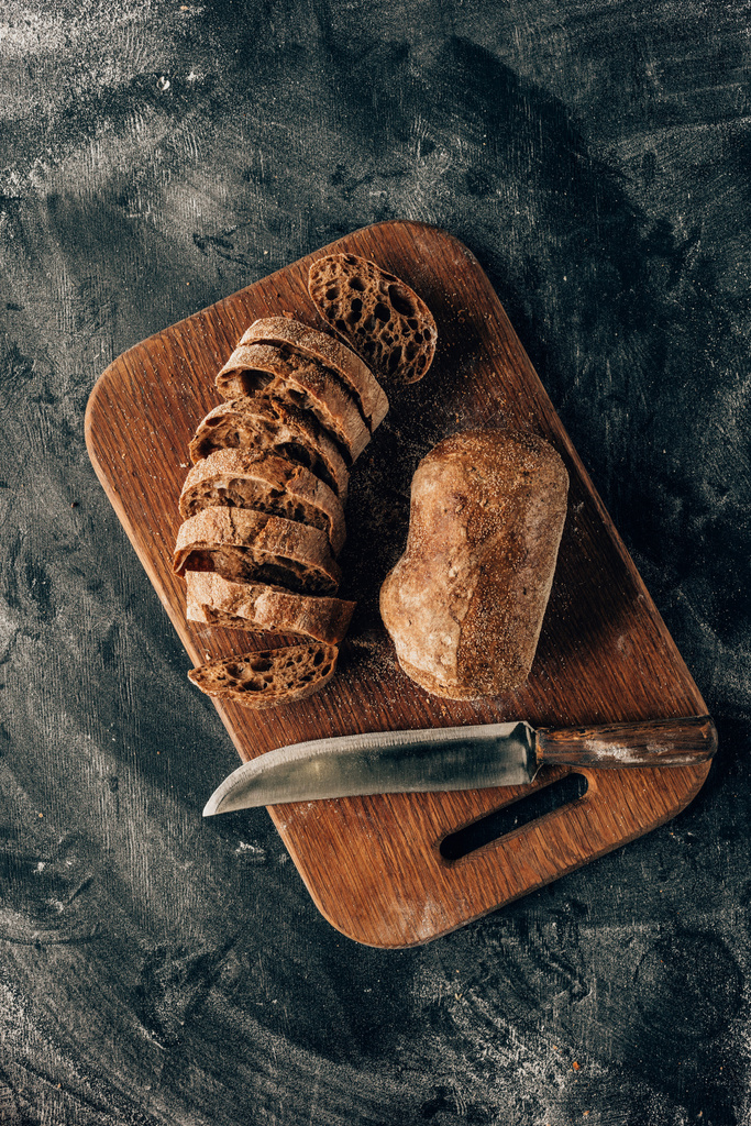 felülnézet rendezett darab kenyér, a vágódeszka a bőrfelszín liszttel késsel - Fotó, kép