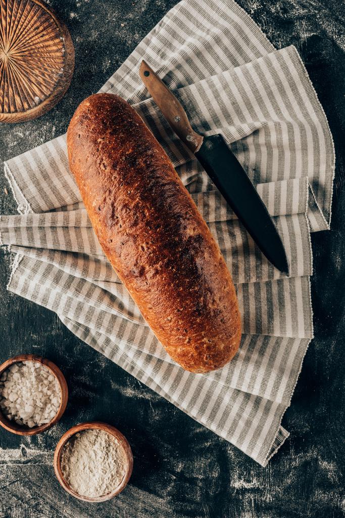 deitado plano com pão em linho e tigelas com farinha perto de mesa escura
 - Foto, Imagem