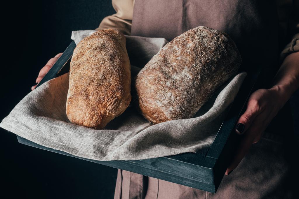 siyah izole elinde ekmek ile ahşap kutu tutan kadın kırpılmış kadeh loafs - Fotoğraf, Görsel