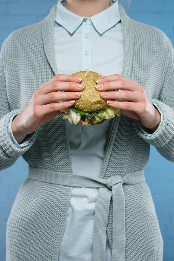 обрізаний знімок жінки, що тримає зелений веганський бургер
 - Фото, зображення