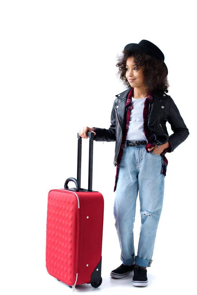 hermoso niño pequeño de pie con el equipaje y mirando hacia otro lado aislado en blanco
 - Foto, Imagen