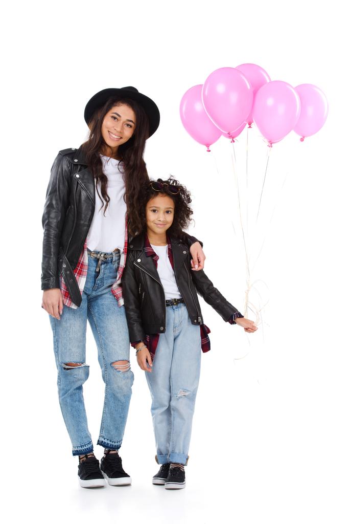 smiling mother and daughter in similar clothes with pink balloons isolated on white - Photo, Image