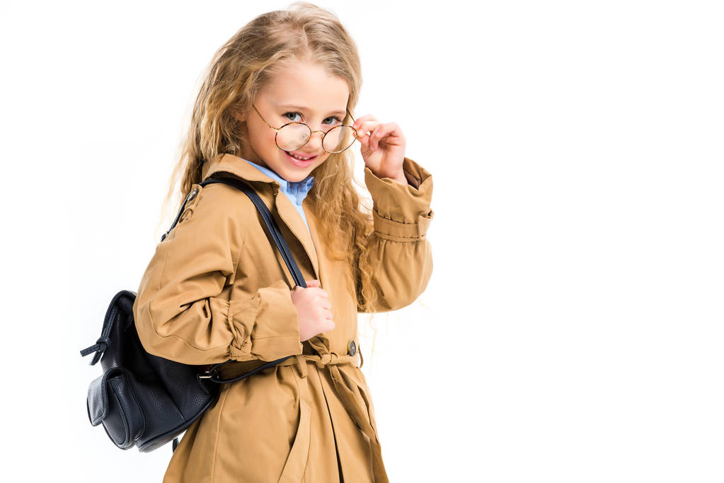 Portrait of smiling kid in trench coat holding glasses isolated on white - Photo, Image