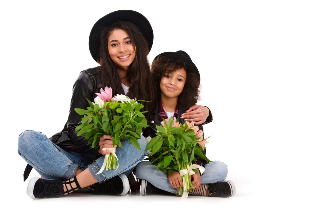 mother and daughter sitting on floor with beautiful bouquets isolated on white - Photo, Image