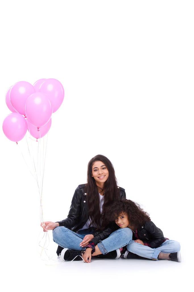 Mutter und Tochter in Lederjacken mit einem Haufen rosa Luftballons auf weißem Grund - Foto, Bild