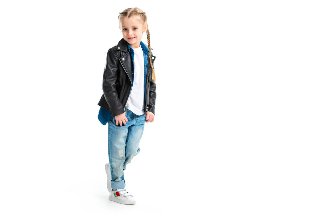 Little stylish kid wearing black leather jacket standing with fingers in pockets isolated on white - Photo, Image