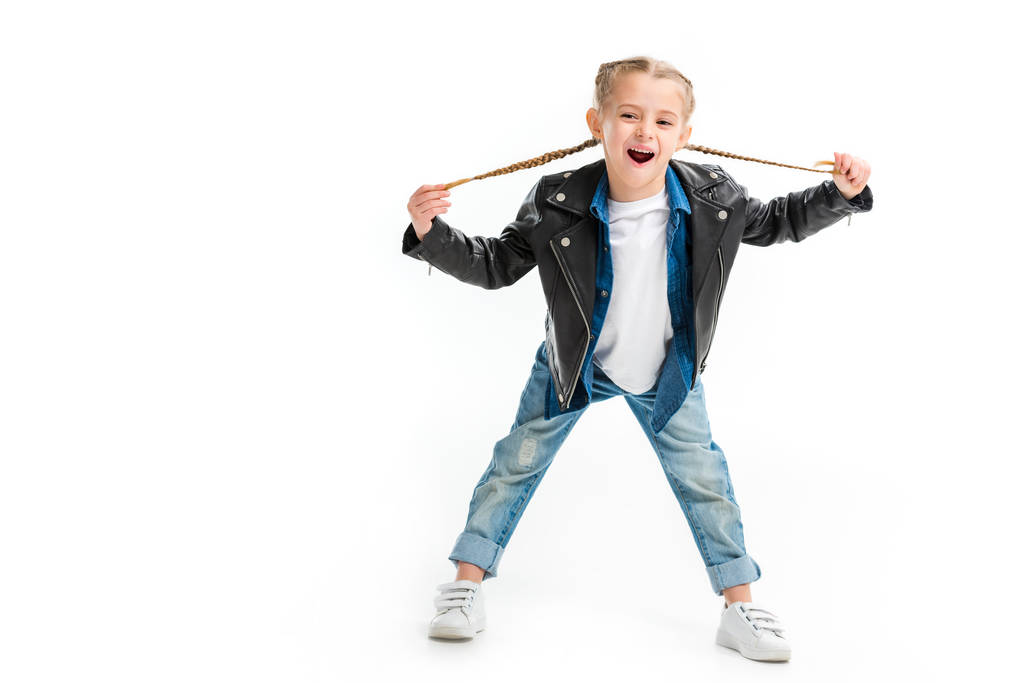 Criança excitada com jaqueta de couro preto segurando suas tranças isoladas em branco
 - Foto, Imagem