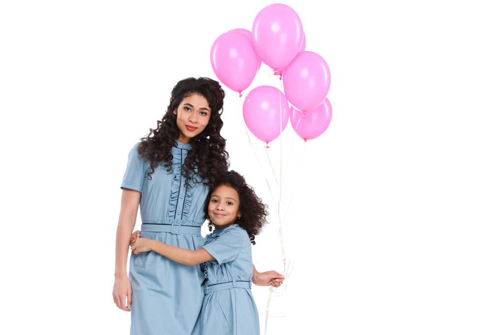 moeder en dochter omarmen met bos van roze ballonnen geïsoleerd op wit - Foto, afbeelding