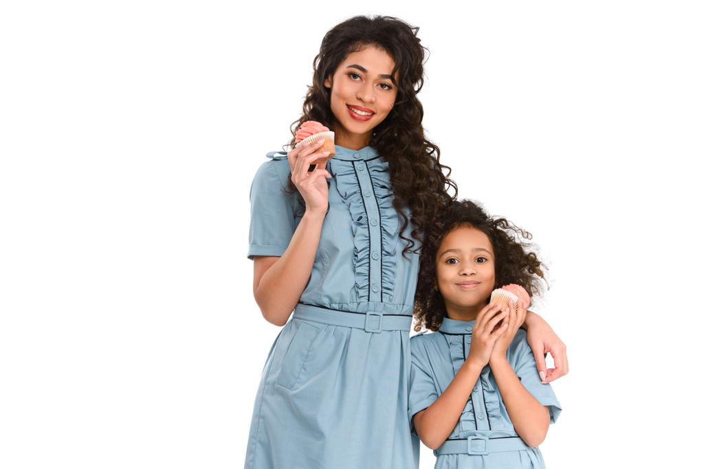 junge Mutter und Tochter mit leckeren Cupcakes isoliert auf weiß - Foto, Bild
