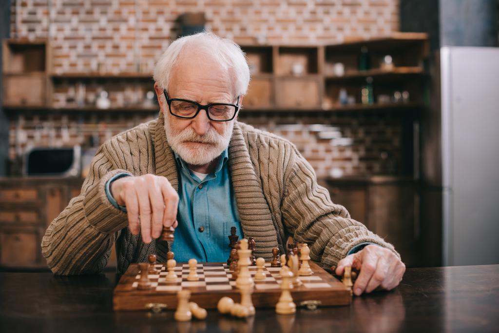 Fiksu vanhempi mies pelaamassa shakkia yksin.
 - Valokuva, kuva