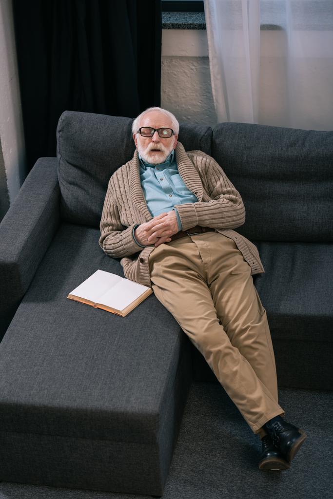 本とソファで寝ている年配の男性 - 写真・画像