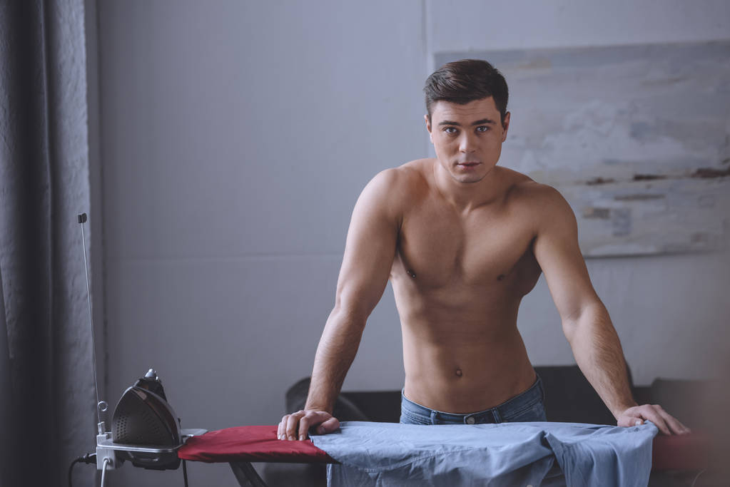 seductive shirtless man leaning on ironing board - Photo, Image