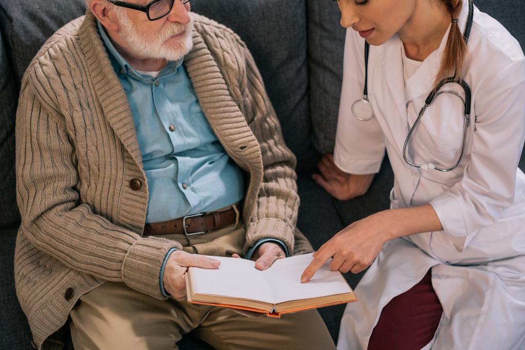 Homem velho paciente e médico discutindo enredo do livro
 - Foto, Imagem