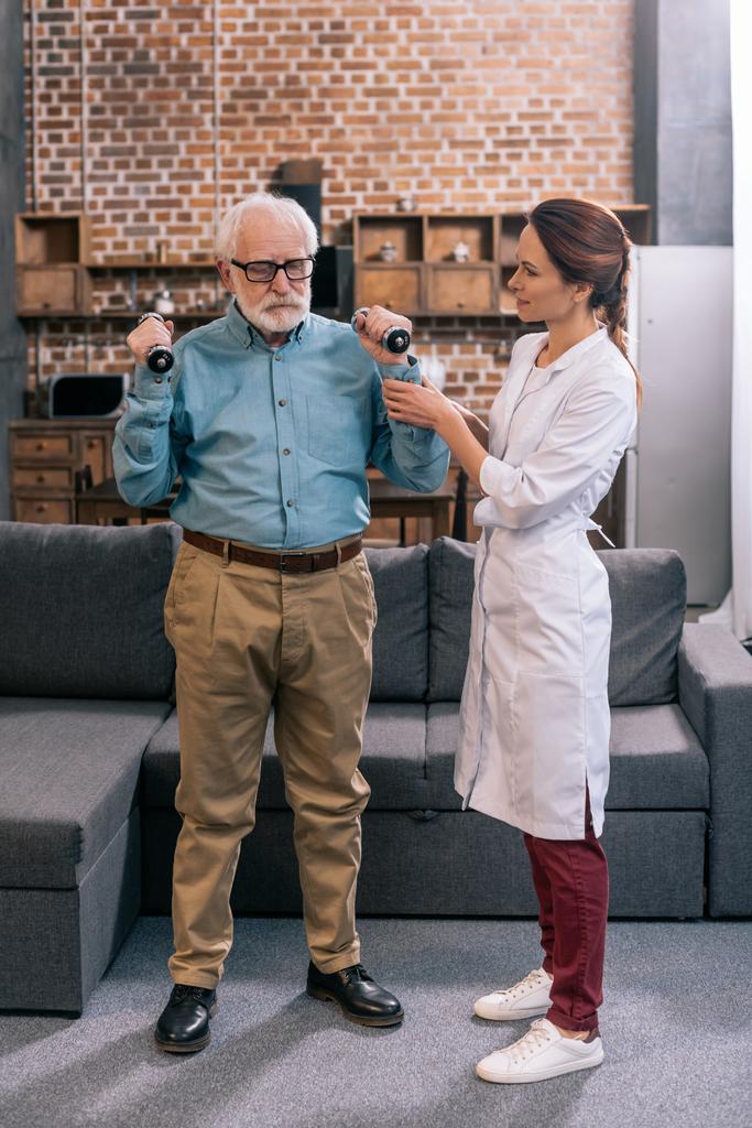 Doctor helping senior man exercising with dumbbells - Photo, Image
