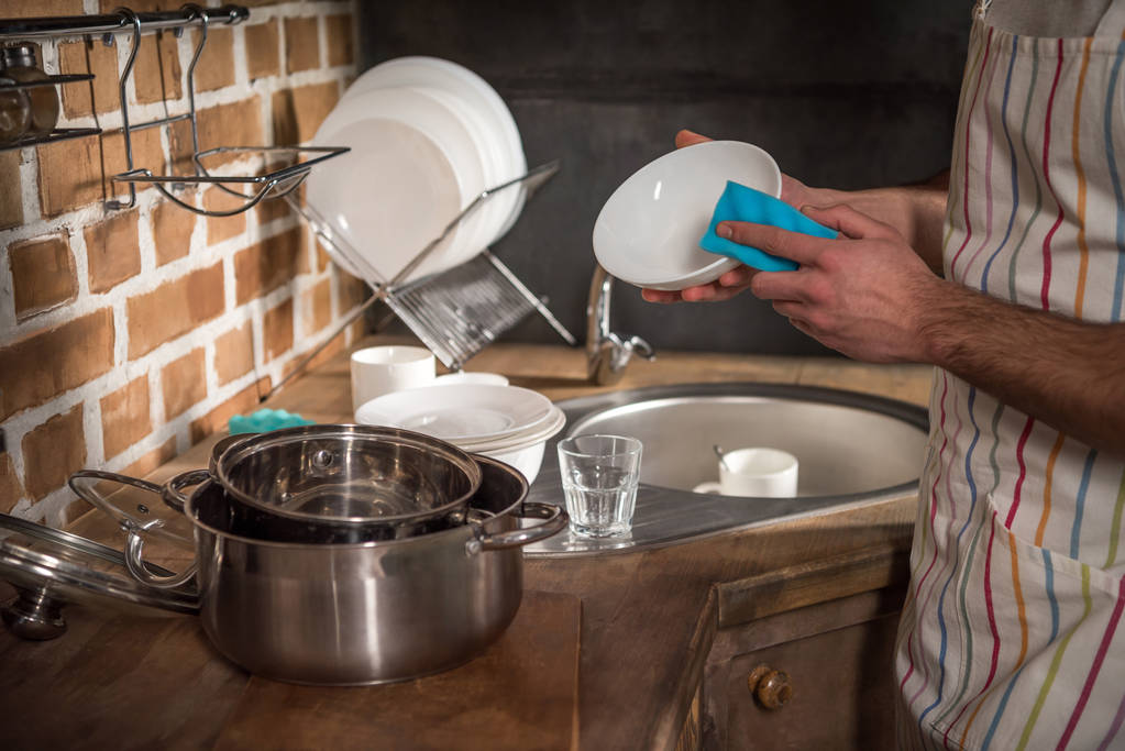обрезанный образ человека, моющего посуду на кухне
 - Фото, изображение