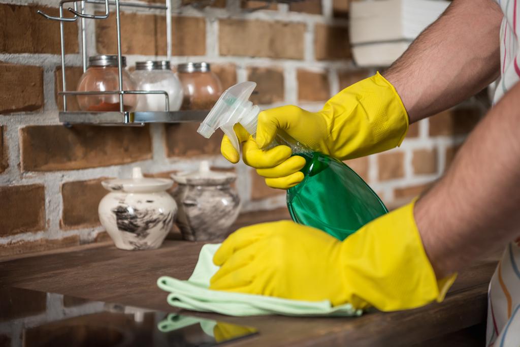 imagen recortada de hombre cocina de limpieza con botella de spray y trapo
  - Foto, Imagen