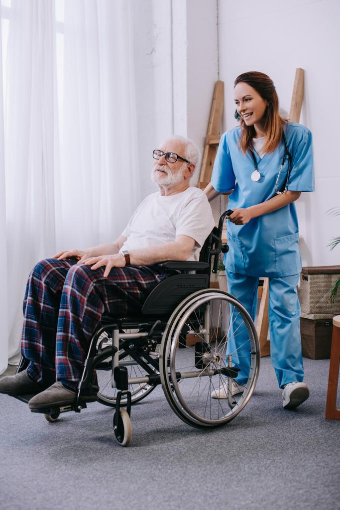 Enfermeira empurrando cadeira de rodas com paciente sênior
 - Foto, Imagem