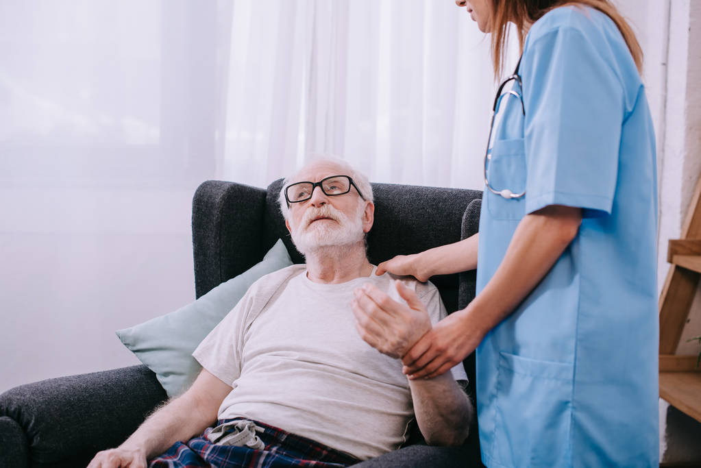 Verpleegkundige controleren heartbeat van senior man - Foto, afbeelding