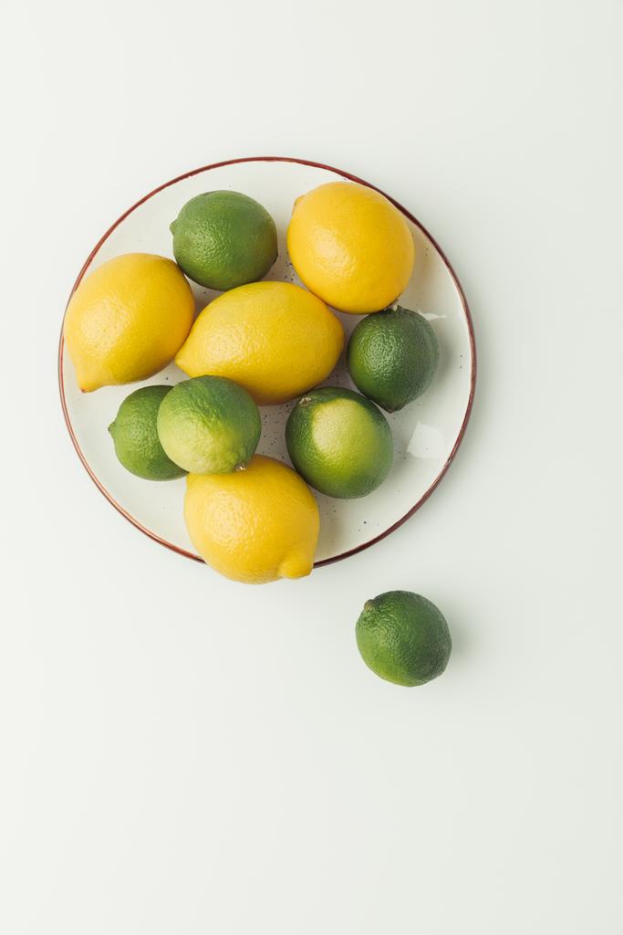 Ansicht von Zitronen und Limetten auf Teller isoliert auf weißem Hintergrund - Foto, Bild