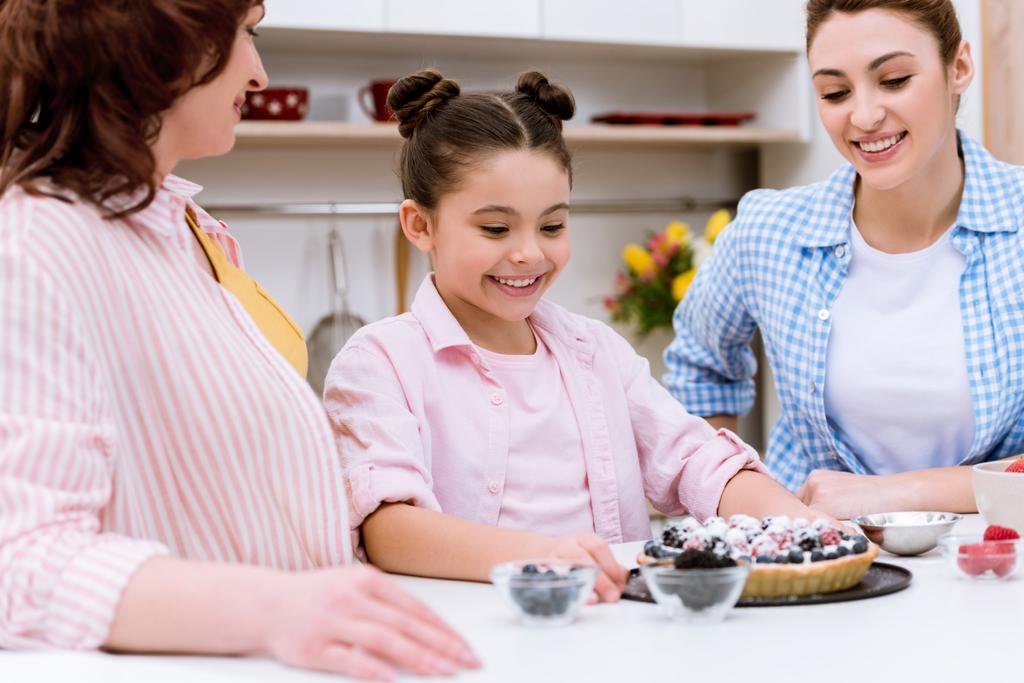три поколения женщин с вкусным десертом на кухне
 - Фото, изображение