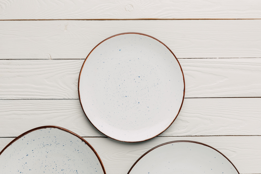 leere Keramikteller auf weißem Holzgrund - Foto, Bild