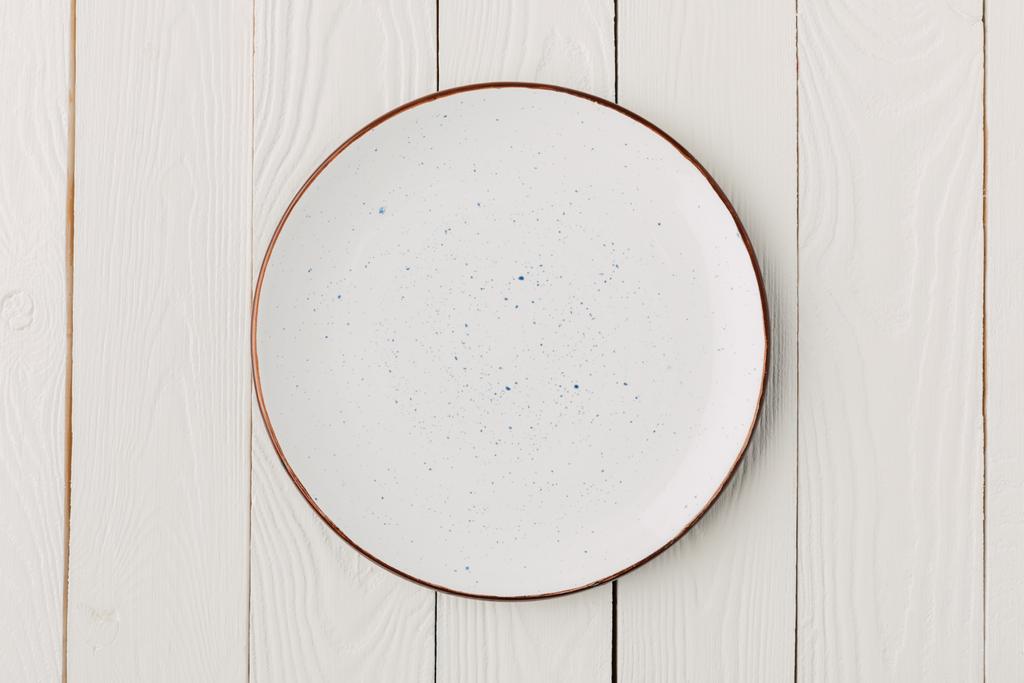 Κεραμικό επισμαλτωμένο πιάτο σε άσπρο φόντο ξύλινη - Φωτογραφία, εικόνα