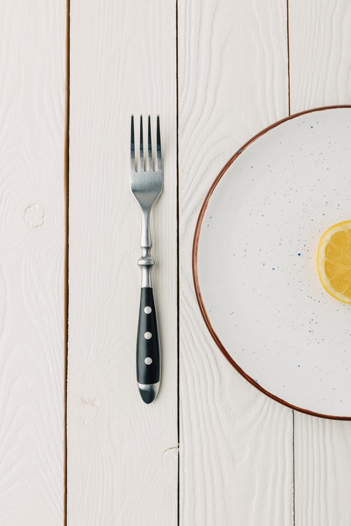 Puolet mehukas sitruuna lautasella haarukka valkoinen puinen tausta
 - Valokuva, kuva