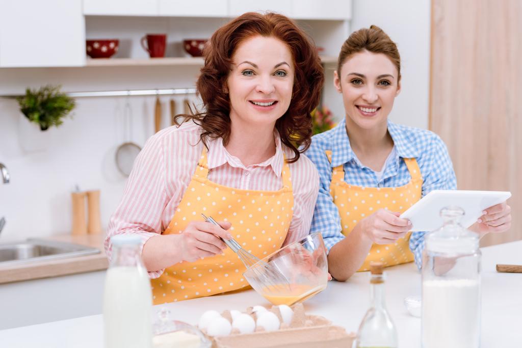 belle jeune femme et sa mère cuisiner ensemble à la cuisine et en utilisant la tablette
 - Photo, image
