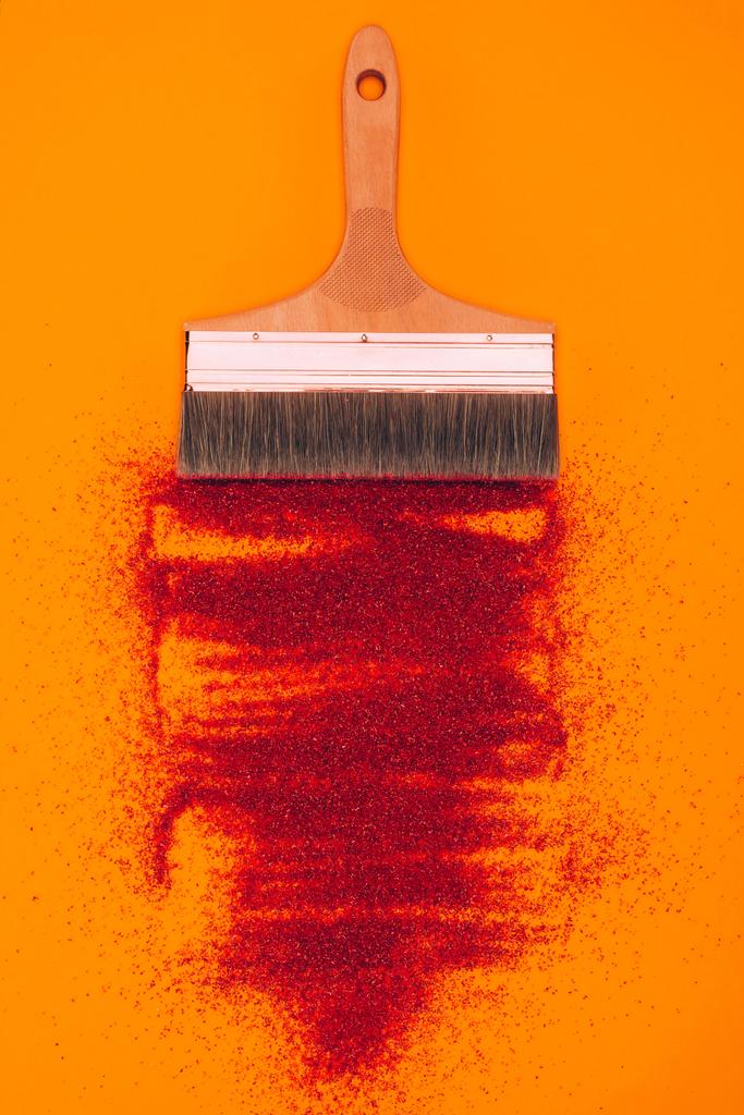 vista superior de arena roja para decoración y cepillo aislado en naranja
 - Foto, imagen