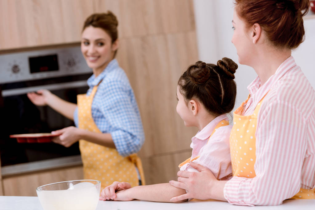 trois générations de belles femmes dans des tabliers pâtisserie ensemble à la cuisine
 - Photo, image