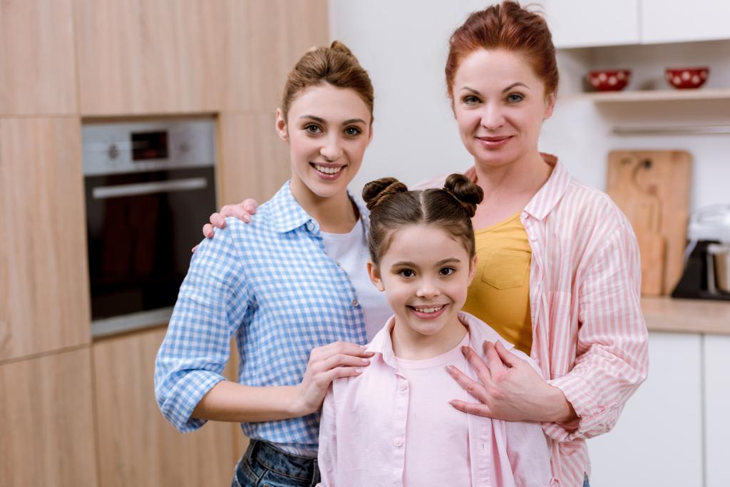 drie generaties vrouwen permanent samen in de keuken en de camera kijken - Foto, afbeelding