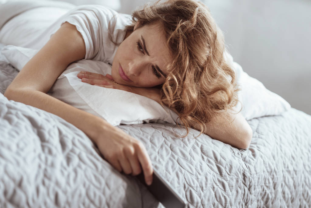 Przygnębiony kobieta ma negatywne myśli, leżąc na łóżku - Zdjęcie, obraz