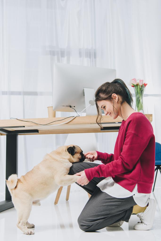 Молодая женщина кормит собаку за рабочим столом
 - Фото, изображение
