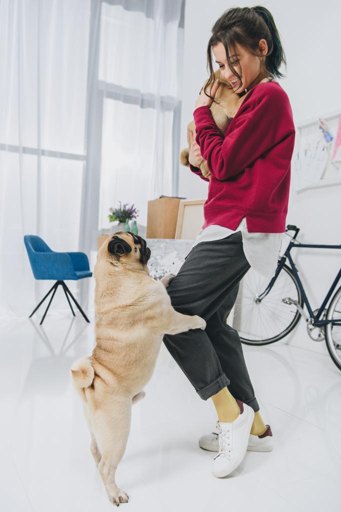 Attractive young girl playing with pugs in stylish room  - Photo, Image