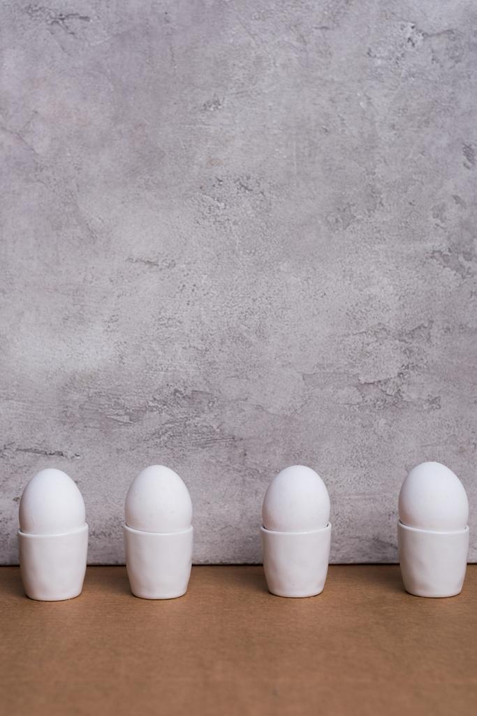 Fila di uova bianche in coppe su fondo grigio
 - Foto, immagini