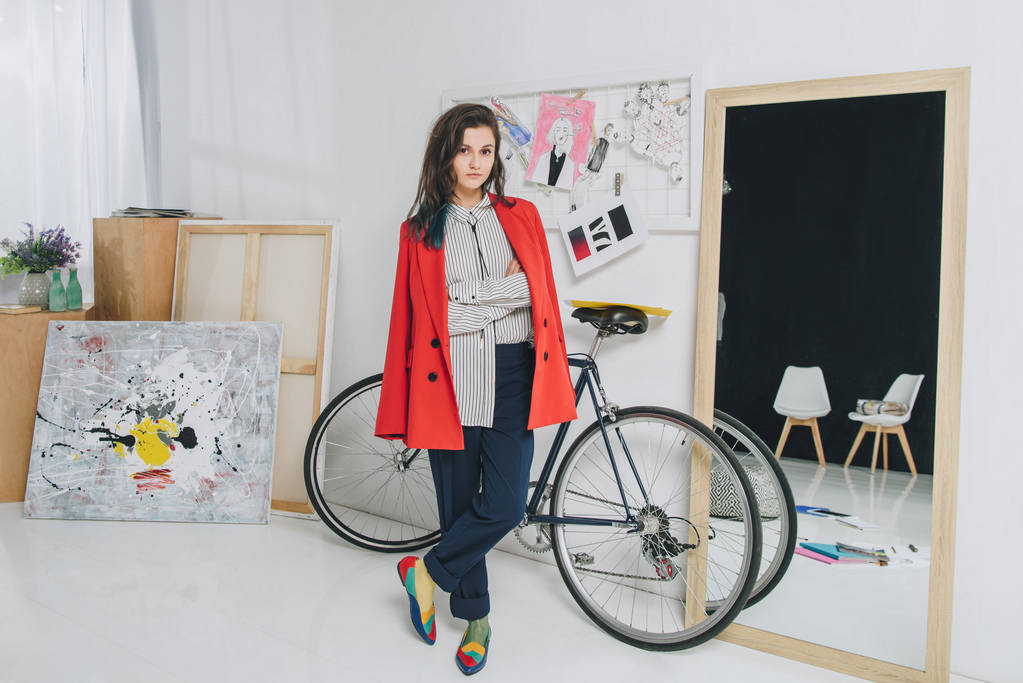 Привлекательная молодая девушка, стоящая на велосипеде в стильном номере
 - Фото, изображение