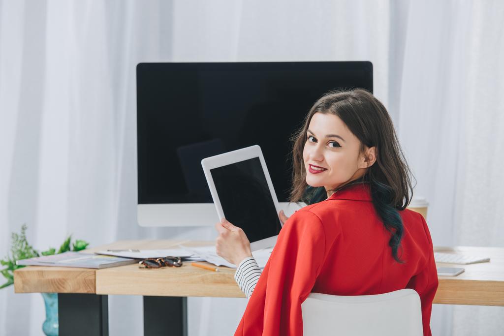 Pretty lady holding tablet by working table with computer - Photo, Image